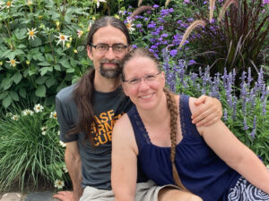 Picture of Eva and Rafael Van Daele-Hunt (Pair O'Dice) sitting in front of some beautiful garden flowers.